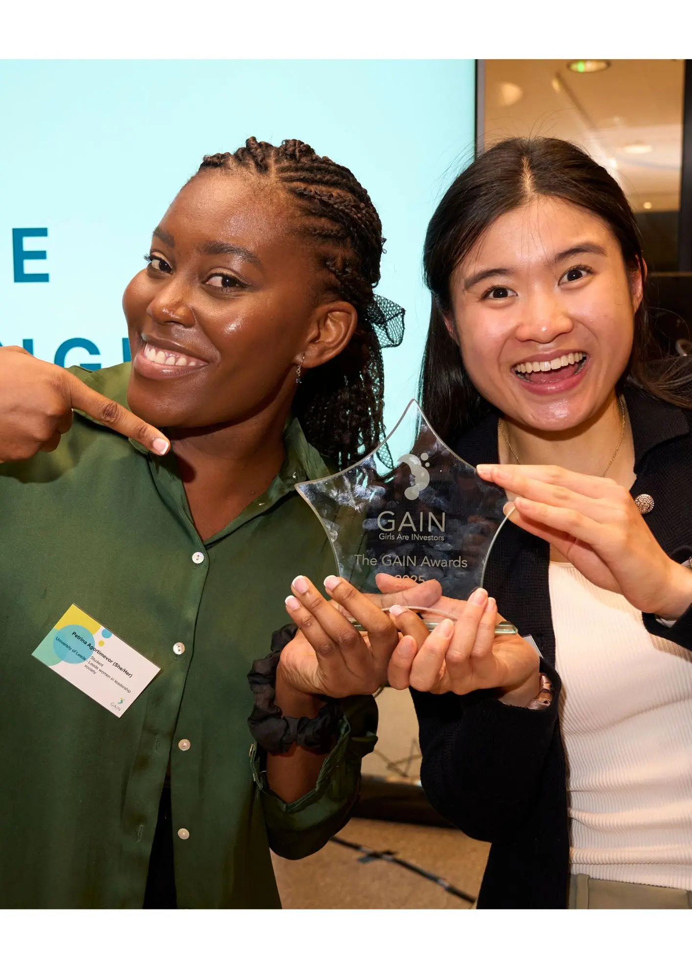 Two winners at the GAIN Awards smiling and pointing to the glass award in their hands.